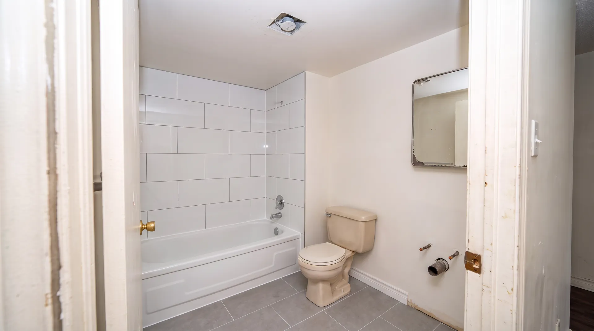 Illustration of the same bathroom with a new white tile surround and grey porcelain floor