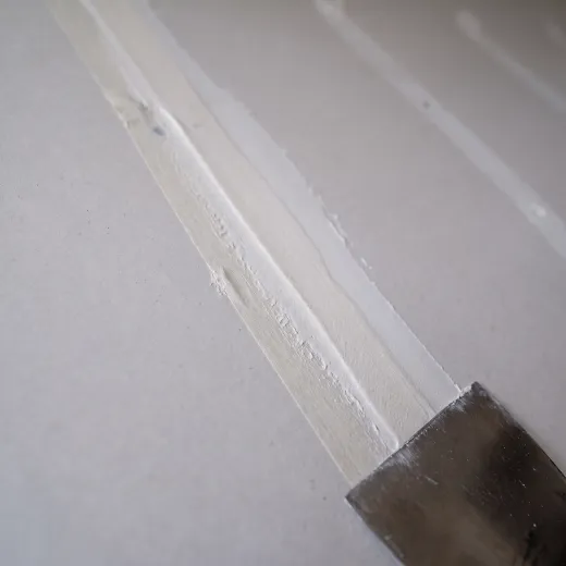Close-up illustration of a taped and mudded drywall seam